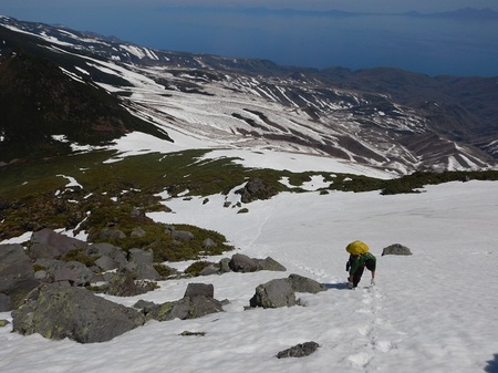 羅臼岳山頂直下にて雪の残る急傾斜を登る職員（2017年5月撮影）