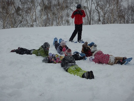 真っ白い雪の上に数人で寝そべりながら人絵を描く羅臼町の小学生（2018年1月撮影）
