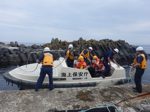 知床岬方面の海岸線にある波止場にて搭載艇に乗り移る救助訓練参加者（2019年7月撮影）